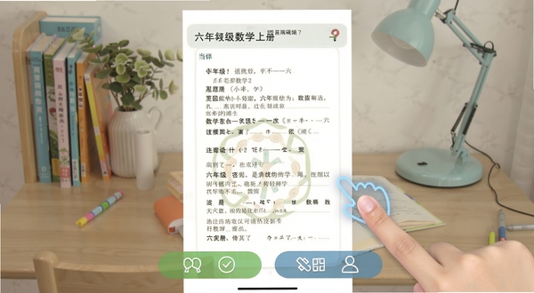 六年级数学上册手机端使用界面截图,画面显示课本页面与底部功能按钮,旁边有手指点击操作示意,背景为居家书桌,简洁明亮风格