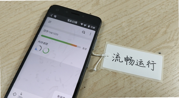 一部入门级安卓手机运行笺影智能扫描,界面显示扫描进度条和内存占用提示,手机旁边有简易手写标签“流畅运行”,背景为浅色木纹桌面,整体风格平实亲民