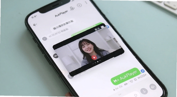 AukPlayer 悬浮小窗与后台播放功能演示,手机屏幕显示悬浮视频窗口叠加在聊天界面之上,背景为柔和浅色桌面,突出多任务操作与音频持续播放的便捷性