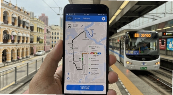 澳门出行APP在安卓手机上的操作界面实拍图,画面展示手机屏幕中的巴士路线规划页面与轻轨换乘方案,背景为澳门街景与轻轨站台,风格写实清晰,适配Boogu模型生成
