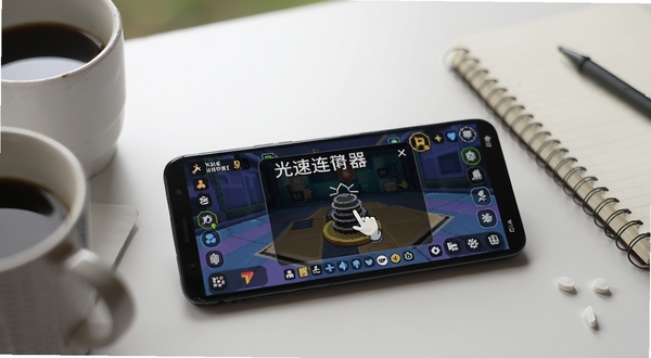 光速连点器在安卓手机上运行的实拍效果图,画面展示一部手机放置在桌面上,屏幕亮起显示游戏界面,一个半透明的悬浮窗显示正在自动点击,旁边有咖啡杯和笔记本,营造轻松挂机的氛围,光速连点器文字标识清晰可见